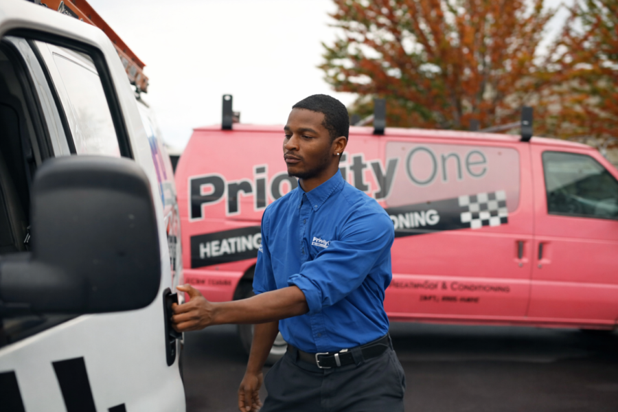 Priority One Heating technician standing beside a service van