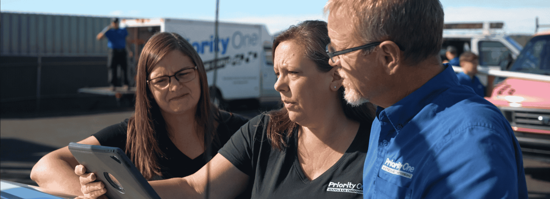Priority One Heating technicians reviewing service details near a van